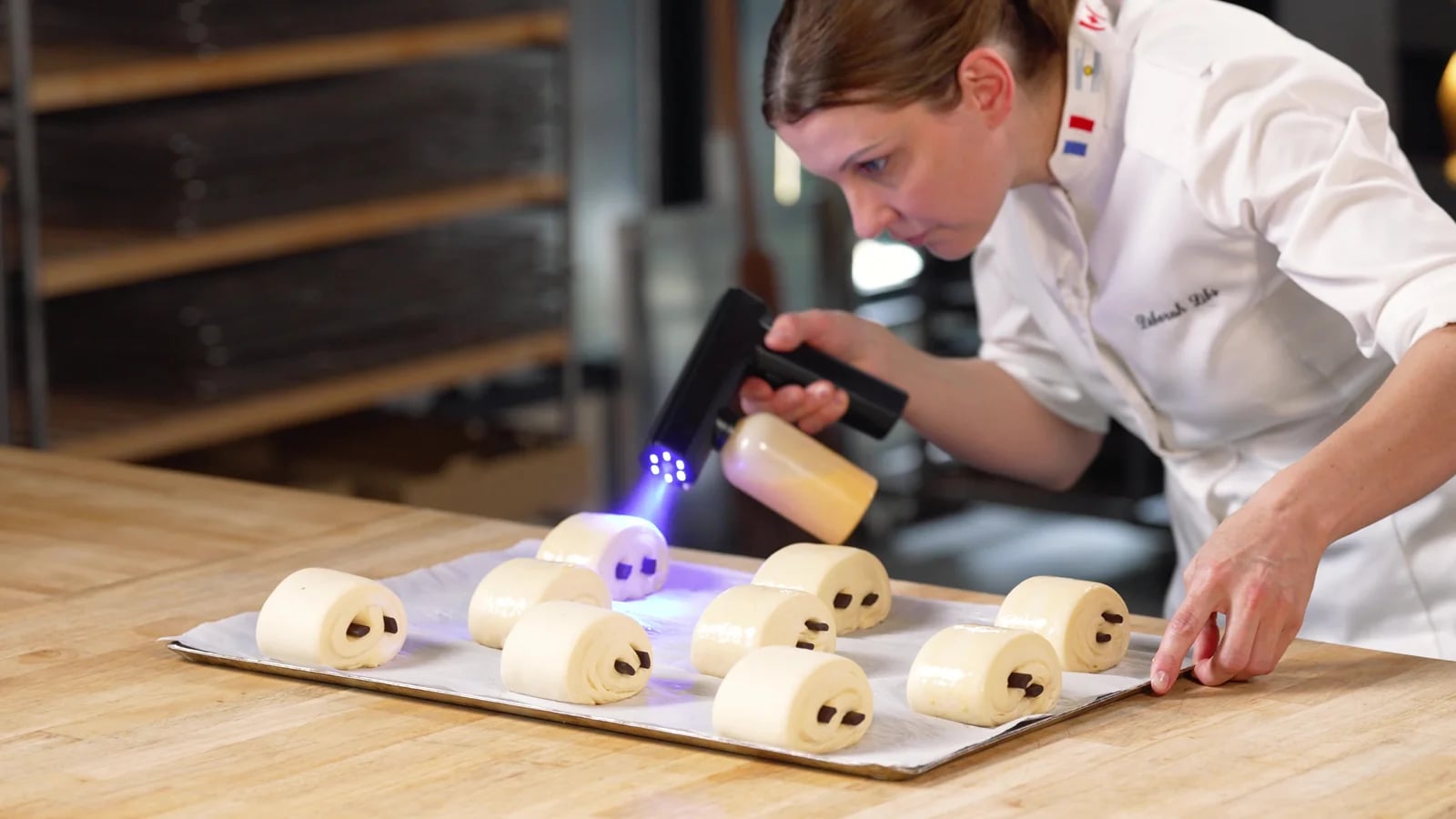 Déborah Libs applique la dorure sur une série de pains au chocolat
